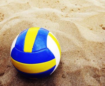 Ein Beachvolleyball liegt im Sand.