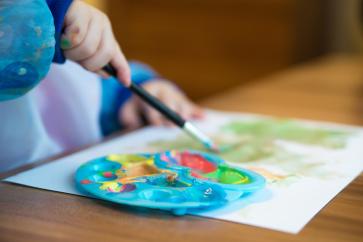 Ein Kind malt mit Wassermalfarbe.