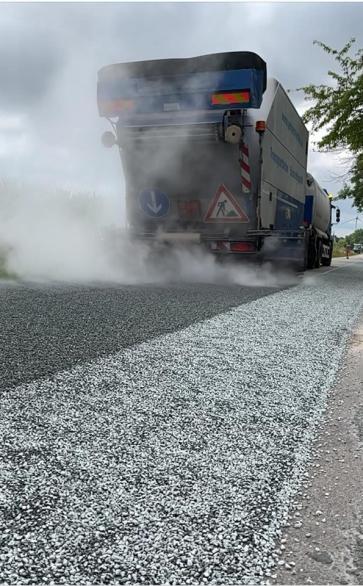 Neuer Straßenbelag wird durch ein Fahrzeug aufgetragen.