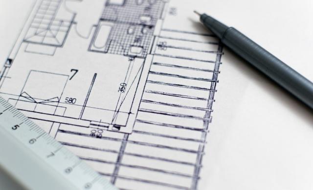 Eine Bauzeichnung eines Hauses, auf der ein Lineal und ein Stift liegen